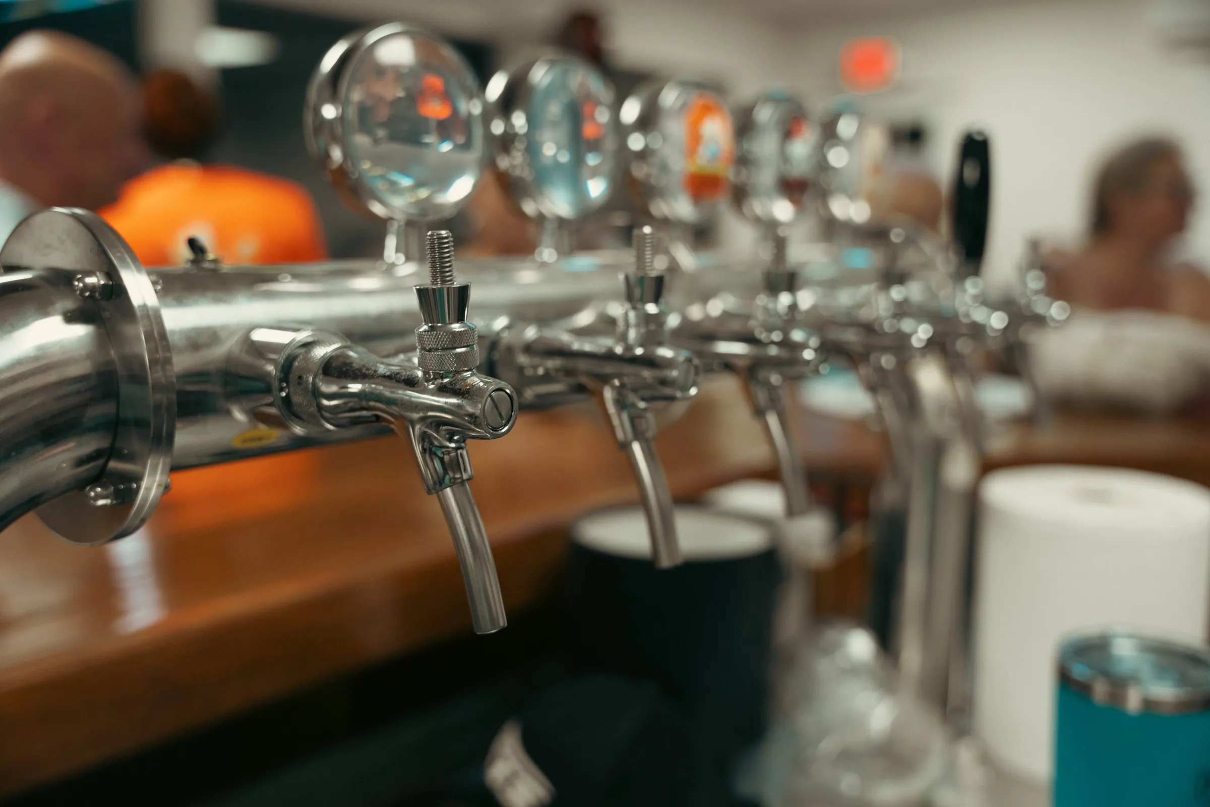 A row of chrome beer taps on the taproom bar